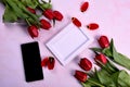 Red tulips bouquet, phone and white photo frame on pink background= Royalty Free Stock Photo