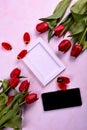 Red tulips bouquet, phone and white photo frame on pink background= Royalty Free Stock Photo