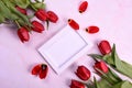 Red tulips bouquet, phone and white photo frame on pink background= Royalty Free Stock Photo