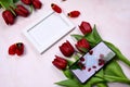 Red tulips bouquet, phone and white photo frame on pink background= Royalty Free Stock Photo