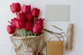 Red tulips in craft paper with greeting card, gift, pencil, scissors on white wood. Mothers day Royalty Free Stock Photo