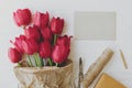 Red tulips in craft paper with greeting card, gift, pencil, scissors on white wood. Mothers day Royalty Free Stock Photo