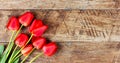 Red tulips flowers on a brown wooden background with a copy space. Royalty Free Stock Photo