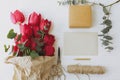 Red tulips with greeting card, gift, pencil, scissors and twine on rustic white wood flat lay Royalty Free Stock Photo