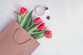 red tulips in paper bag with perfume. Flower card with beautiful bouquet, gift with copy space Royalty Free Stock Photo