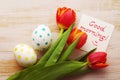 Red tulips, two easter eggs and empty white card with text Good morning! on a wooden surface Royalty Free Stock Photo