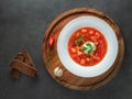 Red ukrainian borscht in white plate on wooden plate with dark bread