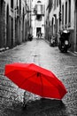 Red umbrella on cobblestone street in the old town. Wind and rain