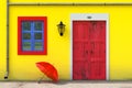 Red Umbrella in front of Retro Vintage European House Building with Yellow Wall, Red Door and Blue Windows, Narrow Street Scene. Royalty Free Stock Photo