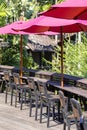 Red umbrella, wooden chairs and table in empty cafe next to the sea on the tropical beach, Thailand