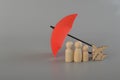 Red umbrella, wooden doll family and airplane toy. Insurance coverage concept