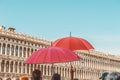 Red umbrellas of tour guides conducting tours on the background of the Piazza San Marco in Venice. Tourist destination