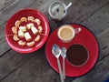 Red utensil, wooden table, cup of coffee and fruits.