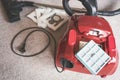 A red vacum cleaner with old and new vacum dust bags and hepa filter laying on a white carpet floor.