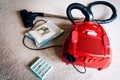 A red vacum cleaner with old and new vacum dust bags and hepa filter laying on a white carpet floor.