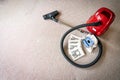 A red vacum cleaner with old and new vacum dust bags and hepa filter laying on a white carpet floor.