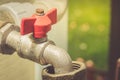 Red valve on a pipe/crane with the gate for water. selective focus