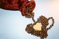 A red velvet bag and coffee beans are laid out in a heart-shaped cup. Roasted coffee beans close up Royalty Free Stock Photo