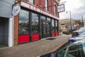 The Red Velvet Bistro in O`neal Plaza with cars parked on the street, bare winter trees, lush green plants with blue sky