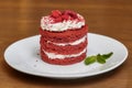 Red velvet cake with cream on white plate, wooden table Royalty Free Stock Photo