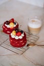 red velvet cakes, portioned, decorated with cherries and strawberries. transparent mug of cappuccino with a cinnamon stick. delici Royalty Free Stock Photo