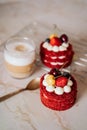 Red velvet cakes, portioned, decorated with cherries and strawberries. transparent mug of cappuccino with a cinnamon stick. delici Royalty Free Stock Photo