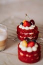 red velvet cakes, portioned, decorated with cherries and strawberries. transparent mug of cappuccino with a cinnamon stick. delici Royalty Free Stock Photo