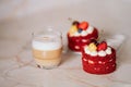 red velvet cakes, portioned, decorated with cherries and strawberries. transparent mug of cappuccino with a cinnamon stick. delici Royalty Free Stock Photo