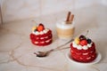 red velvet cakes, portioned, decorated with cherries and strawberries. transparent mug of cappuccino with a cinnamon stick. delici Royalty Free Stock Photo