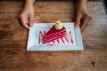 Red velvet cheese cake on white dish in woman hands serving Royalty Free Stock Photo