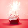 Red velvet cupcake with bengal lights on red background, red muffin. Square image. Valentine`s or birthday card. Magic sparks lig