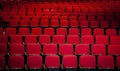 Close up of red theater seats in rows with no people in them shot from the front Royalty Free Stock Photo