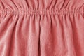 Red velveteen fabric with folds on elastic. Cloth background, velveteen texture.