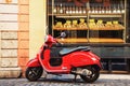 Red Vespa scooter parked in front of the bakery in Rome, Italy