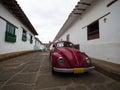 Red vintage retro VW Volkswagen Beetle car vehicle parked in streets road of historic town center Barichara Colombia