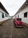 Red vintage retro VW Volkswagen Beetle car vehicle parked in streets road of historic town center Barichara Colombia