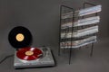 Red vinyl record on turntable, stand with vinyl records