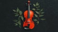 A red violin with black strings and a black bow rests on a black surface, surrounded by green leaves. Royalty Free Stock Photo
