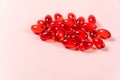 Red vitamin e capsules on pink background