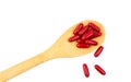 Red vitamins and supplements capsule on wooden spoon isolated on white background with clipping path and copy space for text. Royalty Free Stock Photo