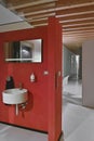 Red wall behind whic there is a round wall-mounted washbasin and