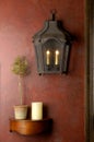 Red wall with lantern and small wooden shelf.