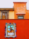 Red wall with religious art in front of historic vintage buildings in san miguel allende Mexico Royalty Free Stock Photo