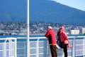 elderly men and woman in windy weather walking along Canada Place Vancouver city center look at Pacific ocean mountains