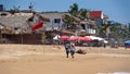 Red flag in front of a beach bar with shade umbrellas Royalty Free Stock Photo