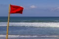 Red warning flag flapping in the wind on beach at stormy weather Royalty Free Stock Photo