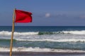 Red warning flag flapping in the wind on beach at stormy weather. Royalty Free Stock Photo