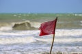 Red warning flag flapping in the wind on beach at stormy weather Royalty Free Stock Photo