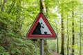 Red warning sign for falling rocks in forest steep incline Royalty Free Stock Photo