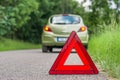Red warning triangle and broken car on the road Royalty Free Stock Photo